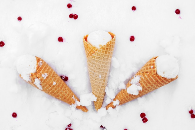 Eiscreme im Waffelkegel mit roten Beeren der Johannisbeere im Schnee