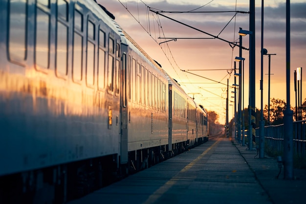 Eisenbahn bei Sonnenaufgang Passagierzug, der vom Bahnhof abfährt