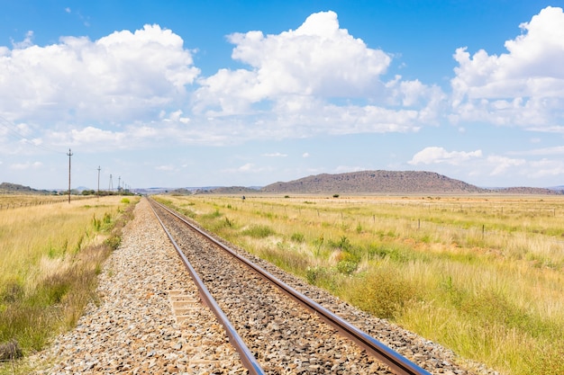 Eisenbahn mitten auf einem trockenen Grasfeld unter dem bewölkten blauen Himmel