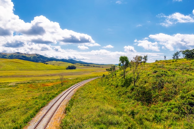 Eisenbahn- und Landschaftslandschaft mit grünen Hügeln und blauem Himmel
