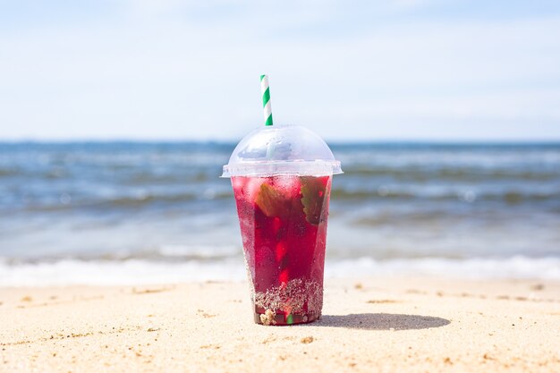 Eisgetränk rote Limonadensoda auf der Strandkirsche oder erdbeerfrischem Saft Seeküstenufersommer-Surfwelle