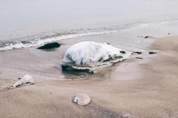 Foto eisiger stein liegt am strand in der nähe des wassers