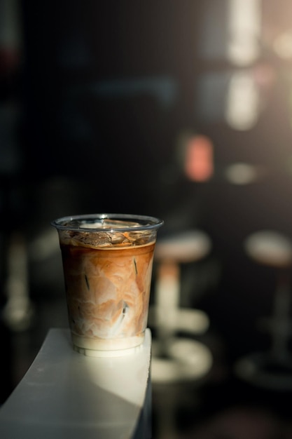 Eiskaffee auf einem Plastikbecher mit Sahne, die hineingegossen wird und die Textur zeigt