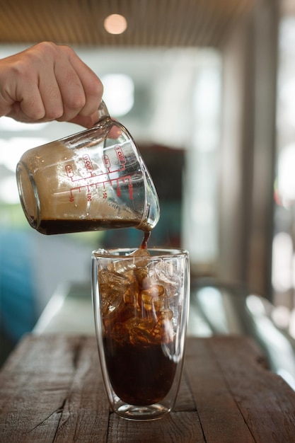 Eiskaffee auf einem Tisch mit Sahne, die hineingegossen wird und die Textur zeigt