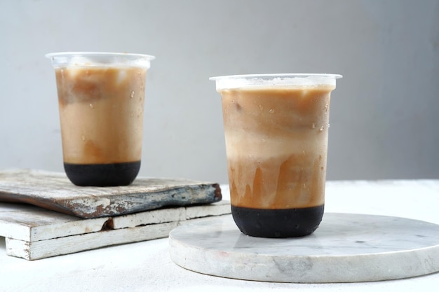 Eiskaffee in einem Plastikbecher auf weißem und grauem Hintergrund