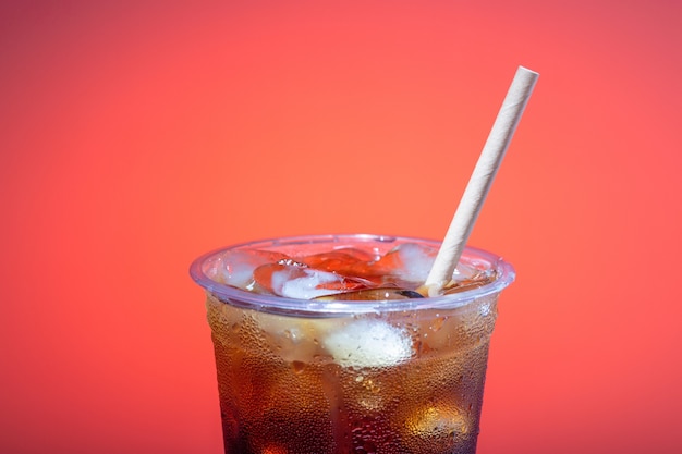 Eiskaffee in einem Plastikglas mit einem Strohhalm auf einer rosa Oberfläche, Kopie des Raumes