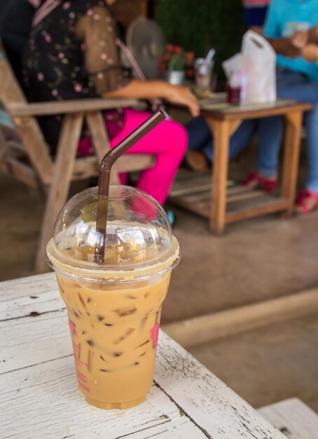 Eiskaffee in Plastikglas auf altem Holztisch