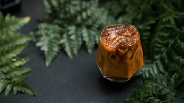 Eiskaffee mit Milch serviert auf dem schwarzen Tisch in einem Café