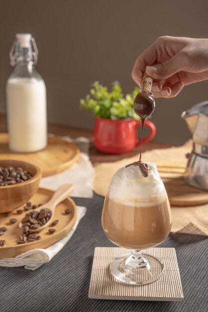 Eiskaffee mit Schlagsahne und Schokoladensirup in Weinglas auf Holztisch