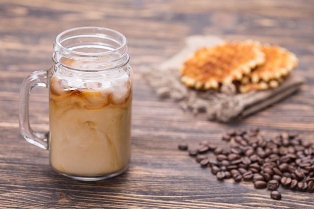 Eiskaffee und Kaffeebohnen im Hintergrund.