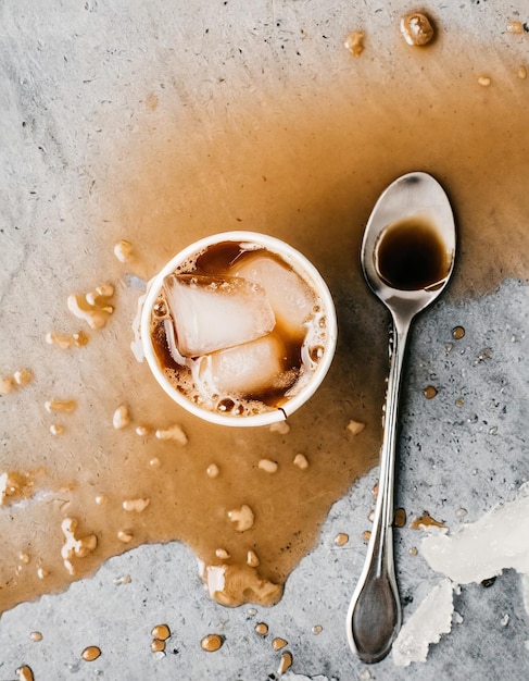 Eiskaffee und Teelöffel auf Marmor verschüttet