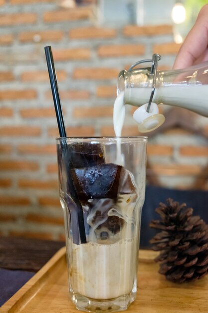 Eiskaffeewürfel mit Milch, die im Retro-Café in Glas gießt