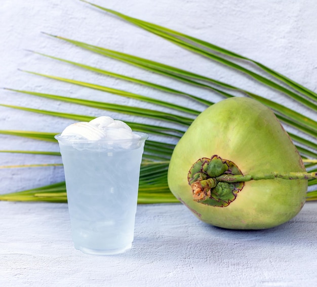 Eiskokosnusswassergetränk in einem Plastikglas und in einer Kokosnuss auf weißem Hintergrund