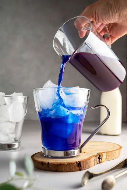 Eislatte mit blauer Schmetterlingserbse Erfrischender blauer Matcha-Latte in einem Glasbecher mit Eiswürfeln