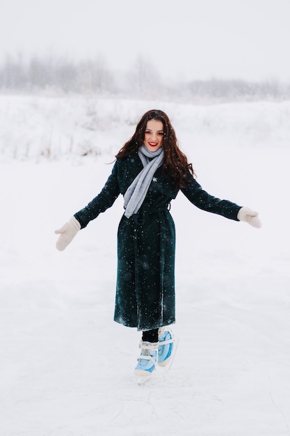 Eislaufen der jungen Frau draußen auf einem Teich an einem eiskalten Wintertag