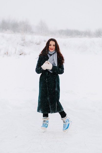 Eislaufen der jungen frau draußen auf einem teich an einem eiskalten wintertag