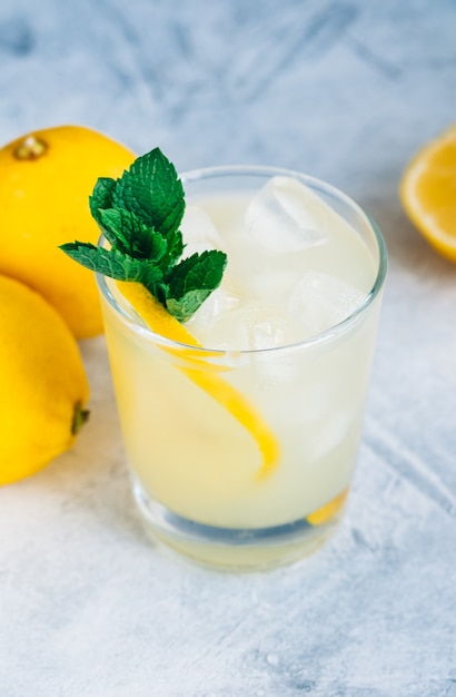 Eislimonade im Glas mit Zitronenstücken, frischer Minze und Eiswürfeln.