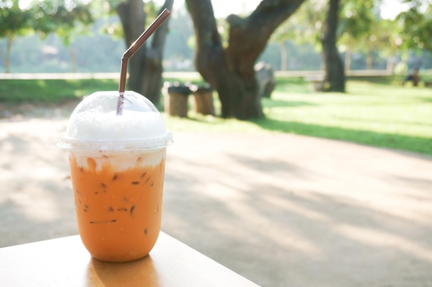 Eismilchtee mit Plastikglas zum Mitnehmen auf Holztisch im Garten