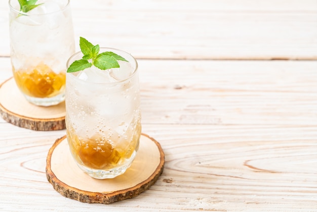 Eispflaumensaft mit Soda und Pfefferminze auf Holztisch - Erfrischungsgetränk