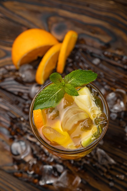 Eistee mit Apfel und Orange auf einem braunen Holztisch Mit Minze dekoriert