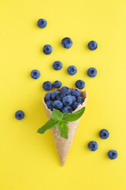 Eiswaffel mit Blaubeere auf gelbem Hintergrund Nahaufnahme Lage vertikal