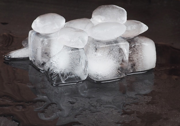 Eiswürfel auf schwarzem Tabellenhintergrund mit Wasser fällt.