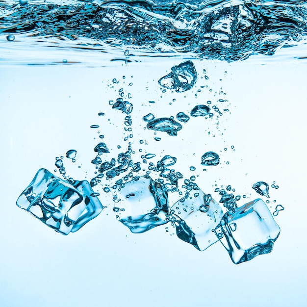 Foto eiswürfel, die ins wasser fallen, sinken auf den grund. abstrakter hintergrund.