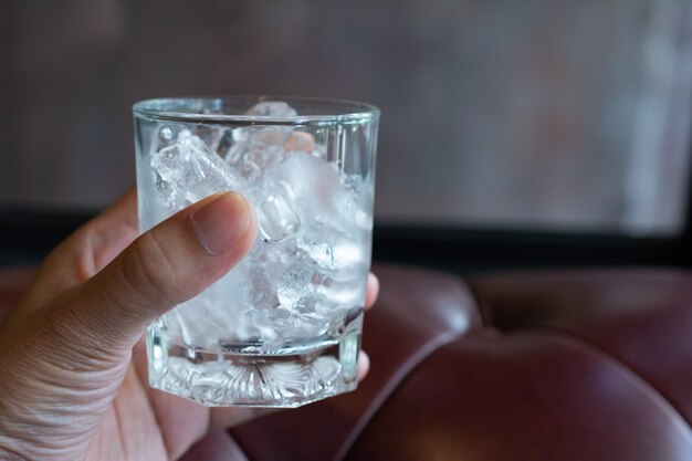 Eiswürfel im Glas mit Sofatapete.