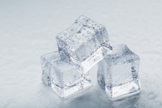 Eiswürfel in Form einer Pyramide mit Wassertropfen in Makroform auf weißem Hintergrund.