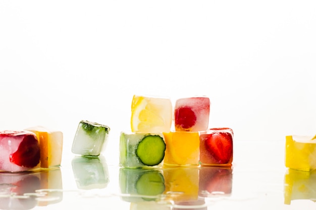 Eiswürfel mit Früchten auf einer hellweißen Oberfläche. Das Konzept von heißem Sommer, Dessert, Eis. Flache Lage, Draufsicht