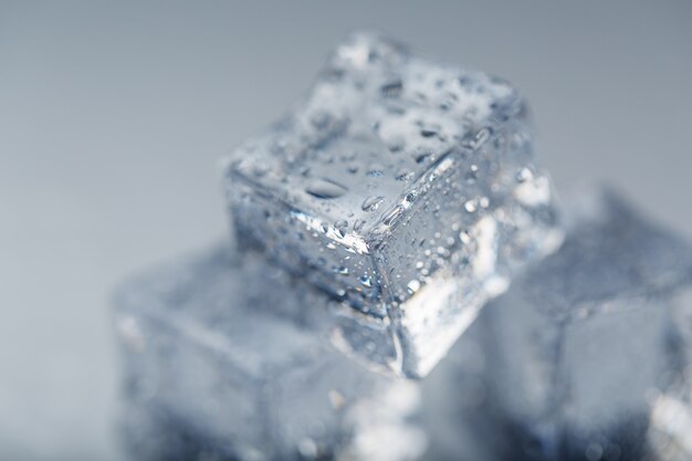 Eiswürfel mit Wassertropfen schließen oben im Makro auf weißem Hintergrund. Erfrischendes Eis. Isolieren