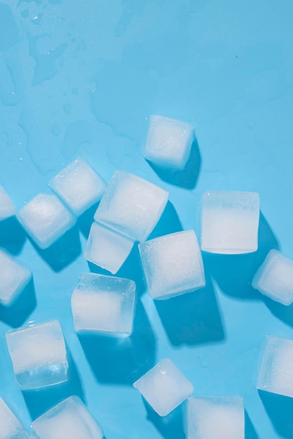 Eiswürfel sind auf einem blauen Hintergrund verstreut.