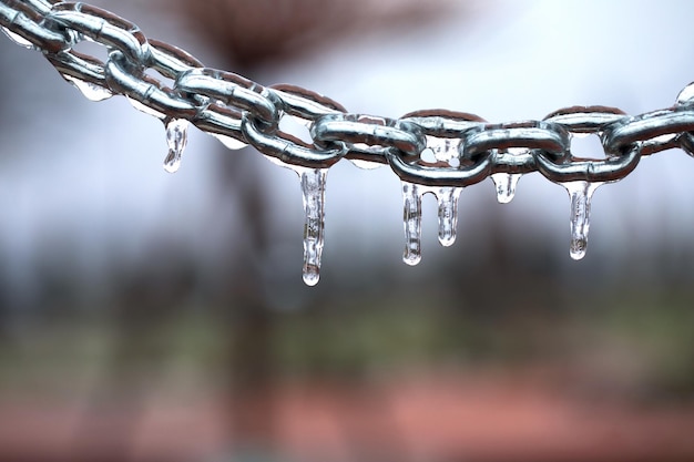 Foto eiszapfen an einer kette, mattiertes metall auf hellem hintergrund.