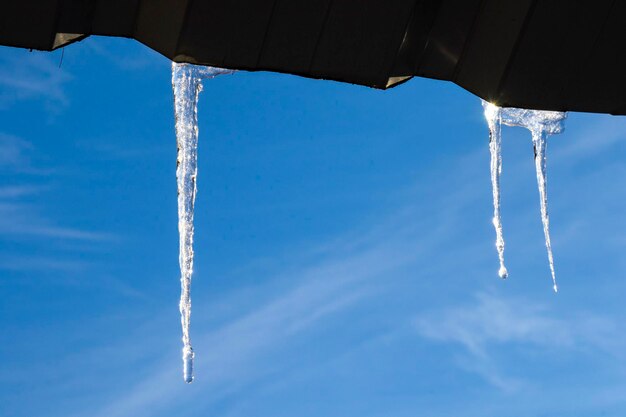 Eiszapfen auf dem Dach, blauer Himmel und Eiswasser, Wintereis