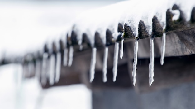 Eiszapfen hängen nach dem Auftauen vom Dach des Hauses