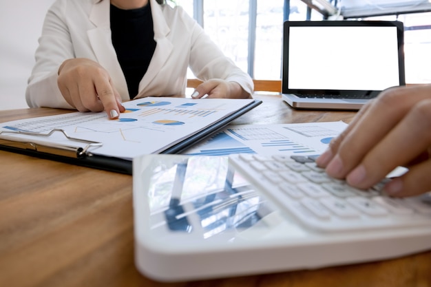 ejecutivo análisis en papel de datos y contador utilizando calculadora en la oficina con pantalla en blanco portátil, concepto de negocio