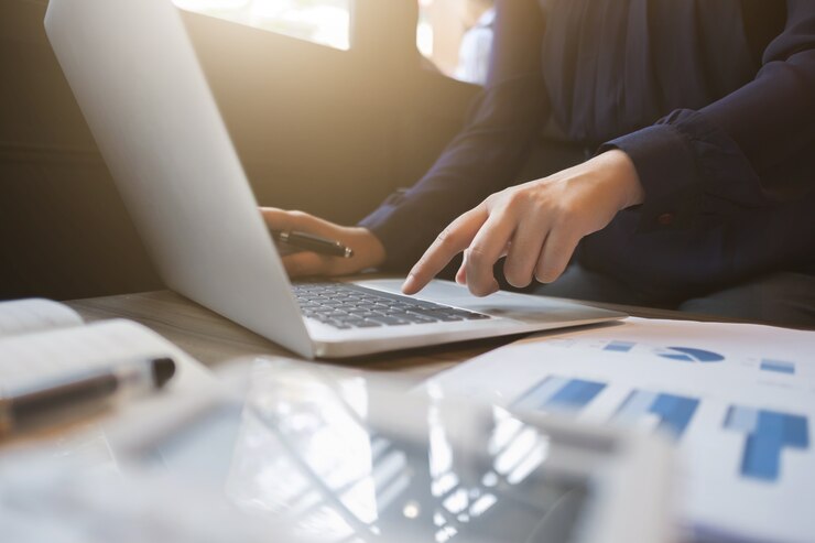 Ejecutivo financiero trabajando en datos de inversión con documentos y computadora portátil