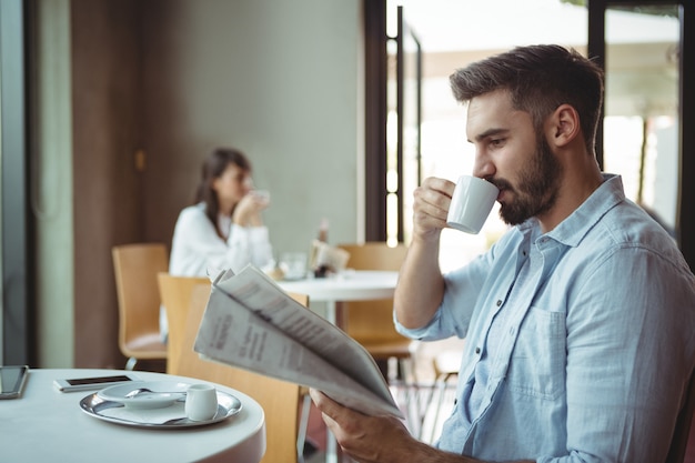 Ejecutivo leyendo el periódico mientras toma un café