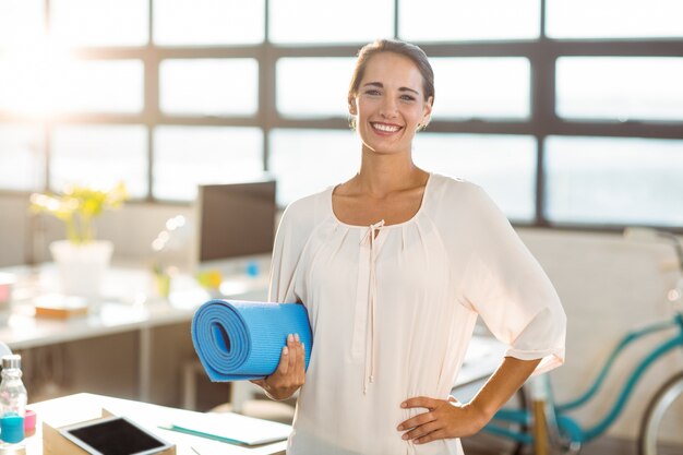 Ejecutivo de negocios femenino con colchoneta de ejercicios