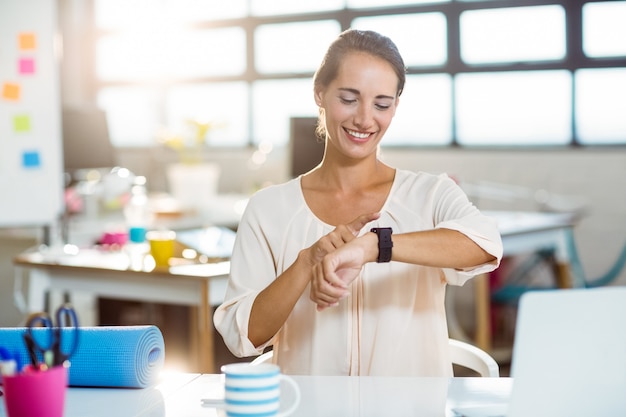 Ejecutivo de negocios femenino que ajusta el tiempo en su reloj inteligente