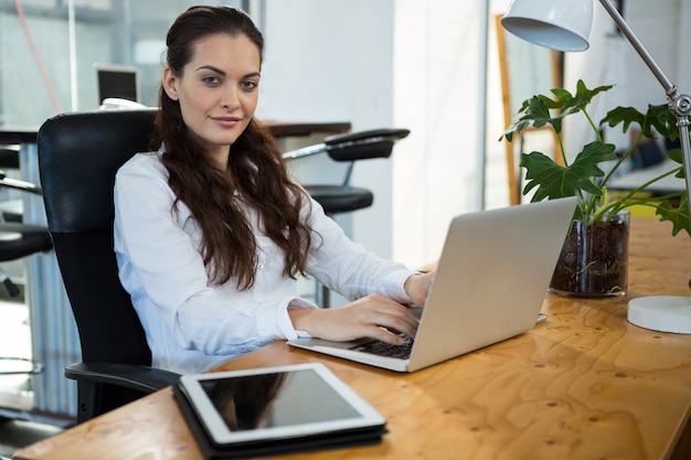 Ejecutivo de negocios femenino que usa la computadora portátil en el escritorio