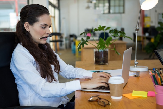 Ejecutivo de negocios femenino que usa la computadora portátil en el escritorio