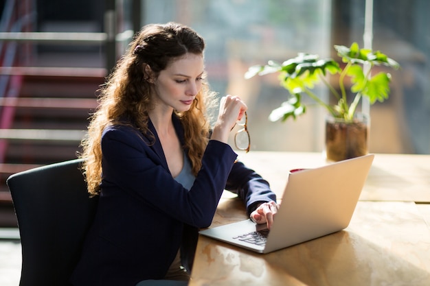 Ejecutivo de negocios femenino que usa la computadora portátil en el escritorio