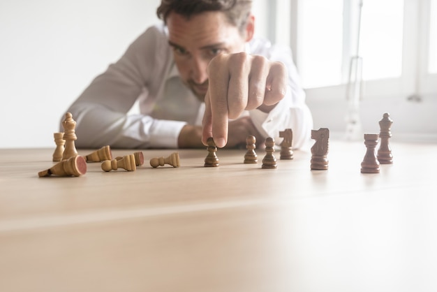 El ejecutivo de negocios hace una estrategia para el futuro colocando figuras de ajedrez en blanco y negro una contra la otra con la mayoría de los blancos caídos con destello de lente