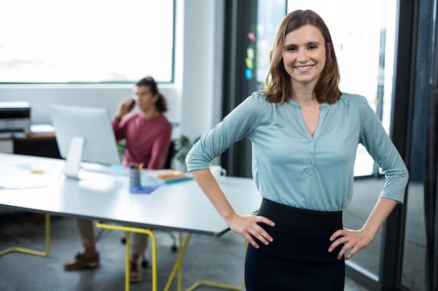 Ejecutivo de negocios de pie con las manos en la cadera en la oficina