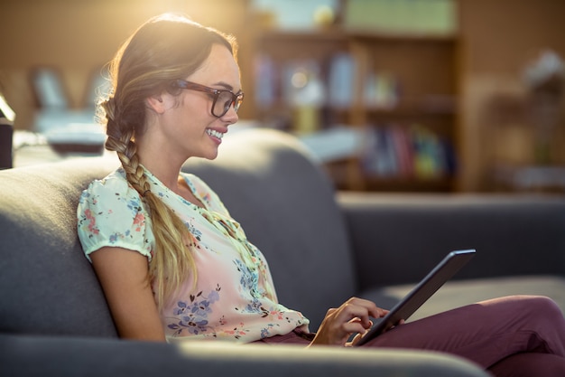 Ejecutivo de negocios sentado en el sofá y usando tableta digital en la oficina