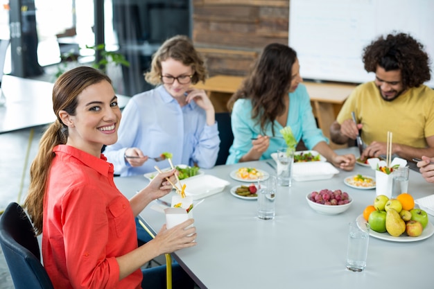 Ejecutivo de negocios sonriente que tiene comida en oficina