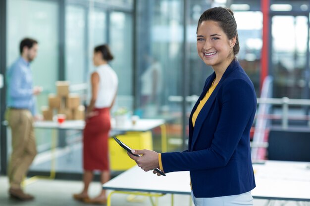 Ejecutivo de negocios sonriente que usa la tableta digital en oficina