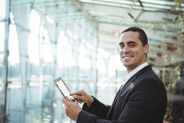 Ejecutivo de negocios sonriente mediante tableta digital en la estación de tren