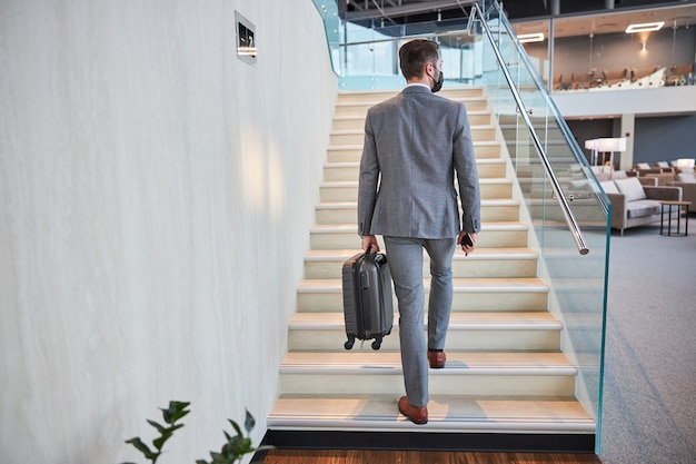 Ejecutivo de negocios subiendo las escaleras con su equipaje de mano